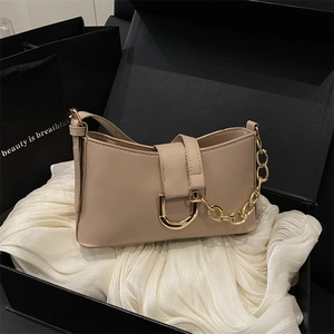 Sac baguette rose poudré avec chaîne dorée sur soie blanche dans un coffret cadeau