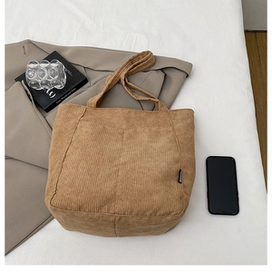 Detail of dark camel corduroy tote bag texture with fashion label on white fabric