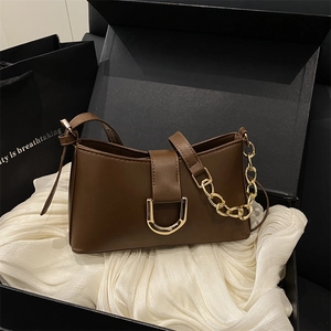 Sac à bandoulière en cuir marron foncé minimaliste avec boucles dorées dans un coffret