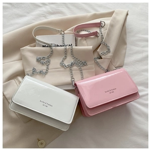 Detail of pink and white patent leather crossbody bags with silver chain straps and flap closure