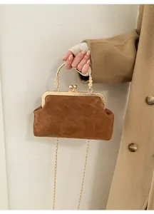 Dettaglio borsa vintage in pelle scamosciata marrone con manico in metallo oro
