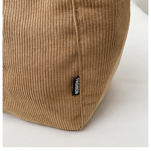 Detailed close-up of brown corduroy tote bag showing ribbed texture and fashion label