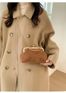 Dettaglio della borsa a catena in camoscio marrone con chiusura a scatto su cappotto beige