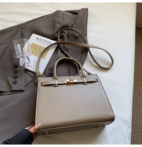 Detailed view of khaki pebbled leather handbag with gold buckle and adjustable strap