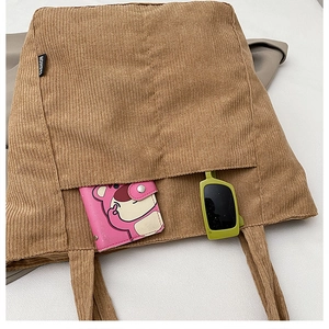 Detail view of khaki corduroy tote bag showing spacious front pocket and fashion label