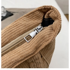 Close-up of silver metal zipper and brown corduroy texture on large tote bag