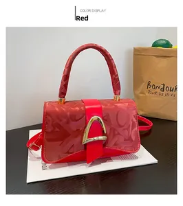 Détail du sac rouge avec boucle fer à cheval dorée et motif monogramme en satin