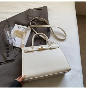 Detail of cream white textured faux leather Kelly bag with gold twist lock and base studs
