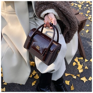 Detail of premium brown leather handbag with gold logo on autumn ginkgo leaves background