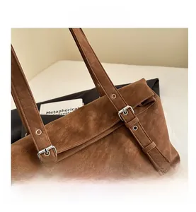 Close-up of brown frosted shoulder bag with silver eyelet straps and buckle detail