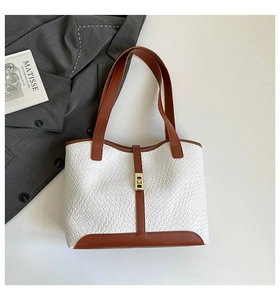 Detail of white crocodile texture tote bag with brown leather trim and gold buckle