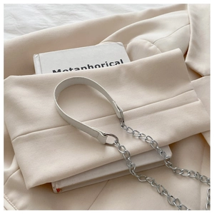 Minimalist creamy white shoulder bag with silver chain strap on a blazer and book