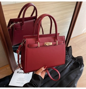Macro detail of wine red Kelly bag showing cross-grain leather and golden metal twist lock