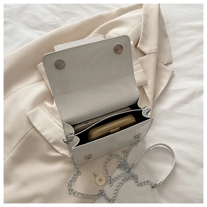 Close-up of interior space and magnetic buckles on white patent leather chain bag