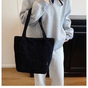Detail of black corduroy tote bag with vertical texture and spacious casual shoulder strap