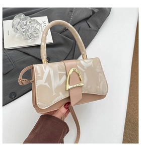 Gros plan du sac beige à imprimé lettres et boucle métallique dorée en forme de D