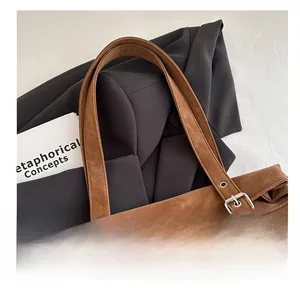 Detail of vintage brown tote bag showing adjustable wide shoulder strap and metal eyelets