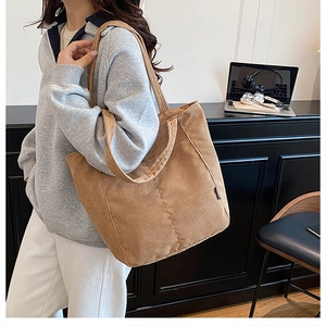 Detailed corduroy texture and brand label on a brown tote bag carried by a model
