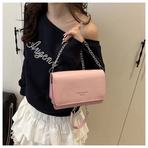 Detailed view of a pink patent leather chain bag with silver hardware on a female model