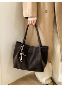 Dettaglio della borsa tote retrò minimalista in marrone scuro con ciondolo decorativo