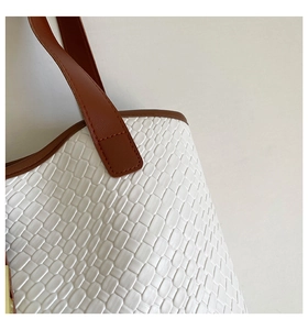 Detail of white woven texture and brown leather strap on a spacious tote bag for women