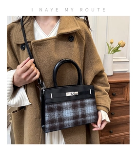 Detail of checkered wool and black leather handbag with metallic turn-lock closure