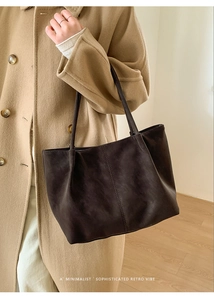 Dettaglio di borsa tote marrone scuro opaco abbinata a un cappotto retrò