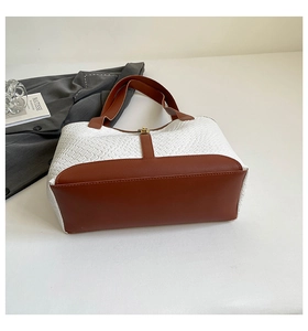Detail of woven fabric tote bag with contrast leather trim and golden hardware buckle