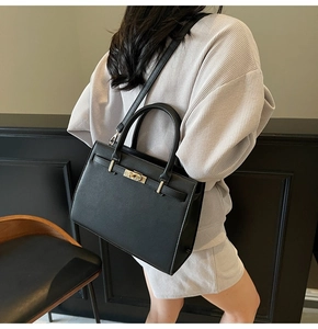 Detail of black pebbled leather tote bag with gold hardware and stylish cylindrical handles