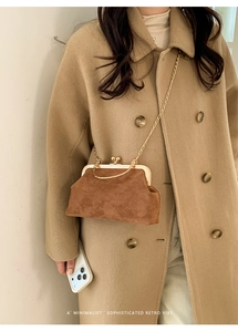 Borsa retrò in camoscio marrone con catena dorata indossata su un cappotto chic