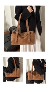 Detail of brown suede tote bag featuring adjustable shoulder strap and retro minimalist style