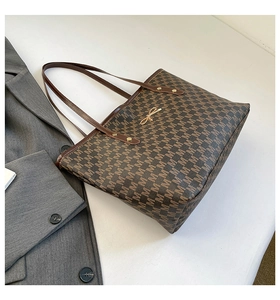 Detail view of large brown tote bag with M-pattern print and gold bow buckle accent