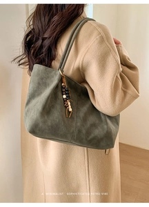 Dettaglio della borsa tote in pelle scamosciata verde scuro con ciondolo in legno