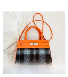 Detail of contrast plaid handbag featuring orange leather trim and silver metal twist lock