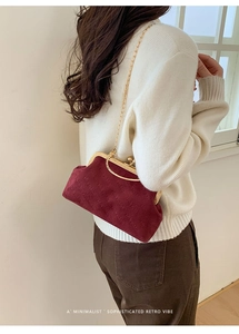 Close-up of retro burgundy velvet clutch with gold metal frame and spherical clasp