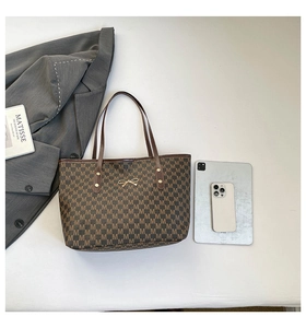 Detail view of large capacity tote bag with brown monogram pattern and golden bow hardware