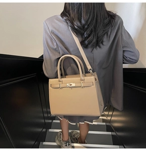 Classic khaki leather Kelly style handbag shown on model with a modern grey blazer