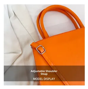 Detail view of the orange PU leather bag showing adjustable shoulder strap with silver buckle