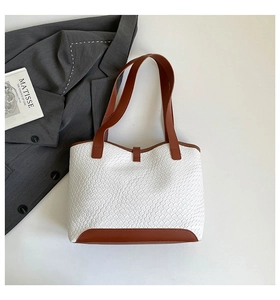 Detail of contrast stitch tote bag with white woven texture and brown leather accents