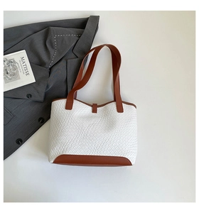 Detail shot of white textured faux leather tote bag with brown straps and side props