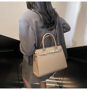 Detail of beige Kelly style crossbody bag with golden hardware and textured surface