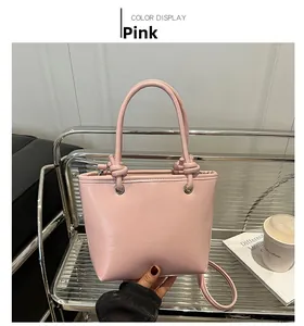 Detail of pink matte leather bucket bag with knotted handle and metal eyelet rings