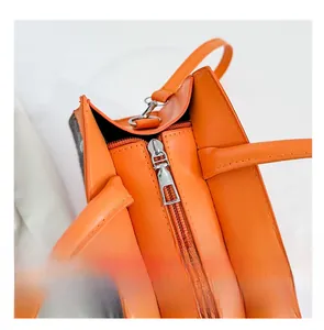 Detailed close-up of the smooth metal zipper and premium stitching on the orange handbag