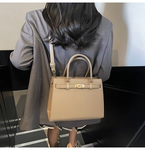 Detail of a khaki leather trapezoid handbag with gold twist lock and shoulder strap