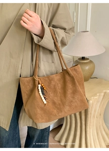 Dettaglio di una borsa tote in pelle scamosciata marrone con nappa decorativa retrò