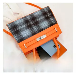 Top view of orange leather handbag with plaid flap and internal space for a smartphone