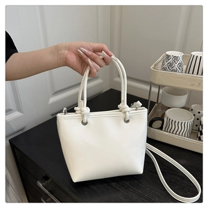 Detail der weißen Handtasche mit geknoteten Griffen und silbernen Metallösen