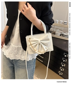 Détail du sac blanc avec nœud en perles, texture en similicuir et chaîne dorée