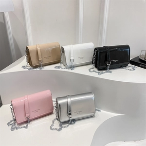 Glossy patent leather crossbody bags with metal chains in five colors displayed on platforms