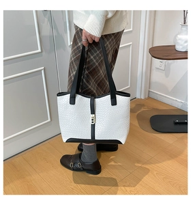Close-up of contrast tote bag with white textured weave and black handle detail